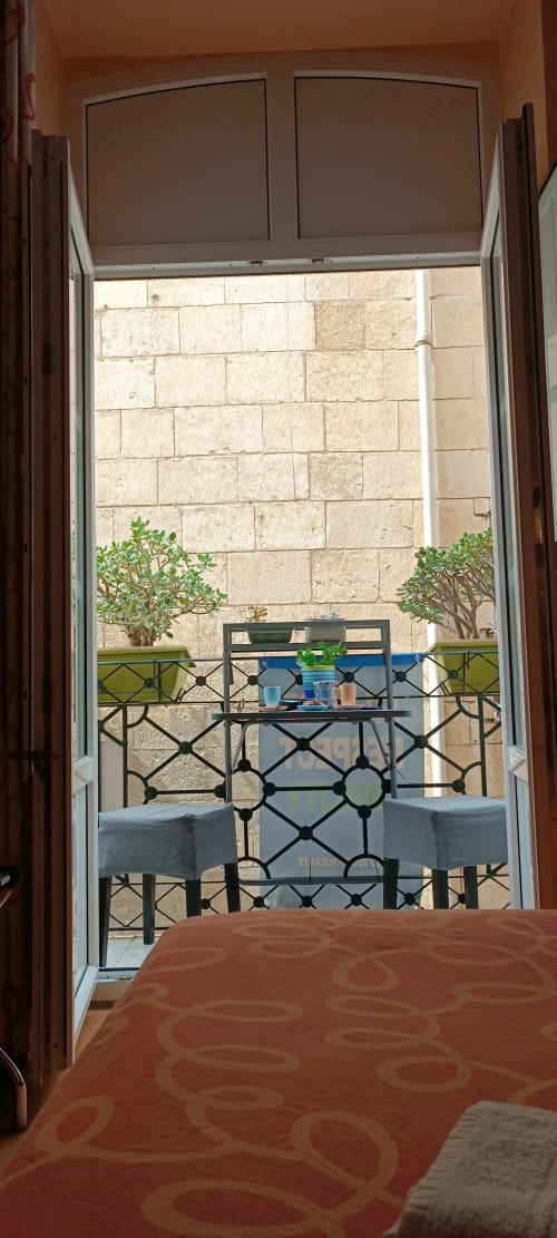Balcón de habitación doble en Pensión Alicante San Nicolás con vistas a pared de piedra, plantas en maceta y barandilla de hierro forjado