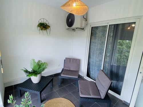 Balcon contemporain de Maisons En Or Cayenne avec salon, plantes et vue mer à travers les portes vitrées