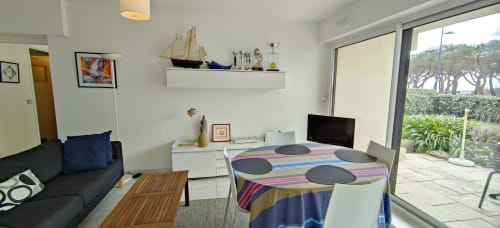 Appartement lumineux à Mer et Maisons avec vue sur mer, canapé noir, lit coloré, bureau avec TV et accès au jardin côtier à La