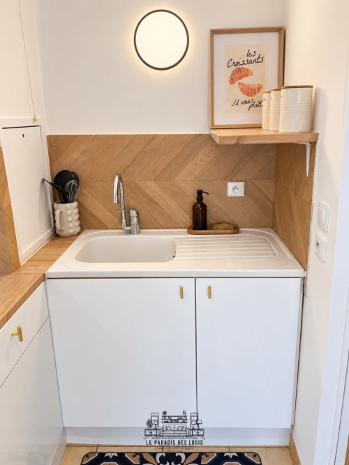 Petite cuisine moderne avec armoires blanches, crédence en bois et évier à l'appartement Le Paradis Des Logis à Saint-Leu-la-Forêt