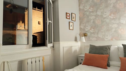 Habitación en Mirador Medieval de Cáceres con vista a torre histórica, paneles blancos, papel tapiz estampado y detalles en naranja