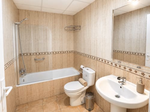 Modern bathroom at Apartamentos El Calón Playa with bathtub, toilet, sink, and tile walls