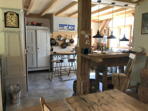Open-plan kitchen and dining area in Les Chalets de l'Eau Rousse cottage with wooden beams, pendant lights, and mountain