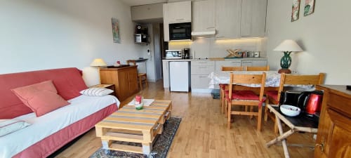 Espace de vie moderne avec canapé rouge, mobilier en bois et kitchenette à Mer et Maisons, La Trinité sur Mer