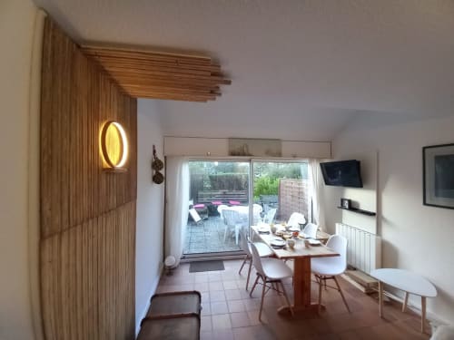 Salle à manger moderne chez Mer et Maisons avec accents bois, table, vue sur jardin par portes vitrées et néon jaune