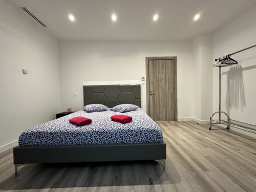 Chambre moderne aux Gites Les Camelias 71 avec lit queen-size, tête de lit hexagonale et porte-vêtements à Oslon
