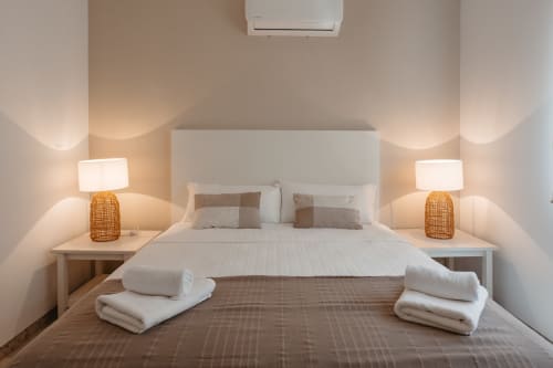 Dormitorio moderno en Las Golondrinas con cama doble, lámparas de noche, toallas blancas y decoración contemporánea en Cap d'Artrutx