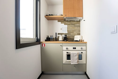 Cozinha compacta no Benefit Collection Porto com forno, fogão, refrigerador e armários de madeira