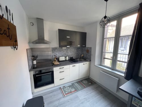 Cuisine moderne dans l'appartement Le Charmant Paillot à Troyes, avec mobilier blanc, plan de travail gris et vue sur la ville