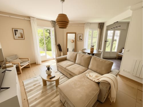 Lumineux salon moderne avec canapé beige, mobilier en bois et vue sur jardin à Le Paradis Des Logis