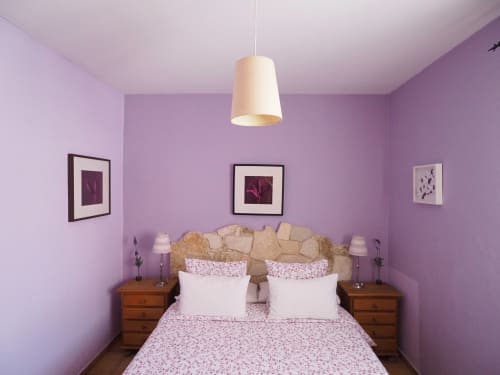 Acogedor dormitorio púrpura en apartamento rural Senda del Duratón con cama doble, mesitas de noche de madera y lámpara colgante