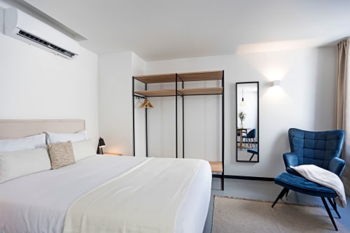 Studio moderno no Porto com cama queen, poltrona azul e closet estilo industrial na Coleção Benefit