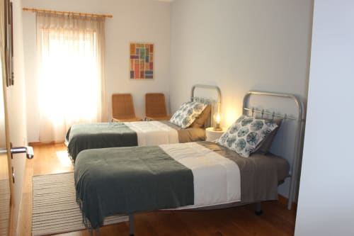 Bright twin bedroom in Seahorse House, Tavira apartment with metal bed frames, patterned pillows, and sea view window