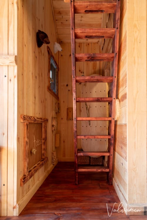 L'échelle de meunier permettant d'accéder à la chambre-mezzanine. Sur la gauche, les trappes d'accès aux lit-cabanes.