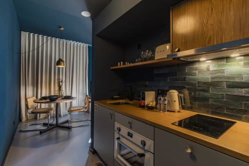 Modern kitchen in Porto hotel apartment with wooden counters, dark backtile, stainless appliances, and blue accent wall