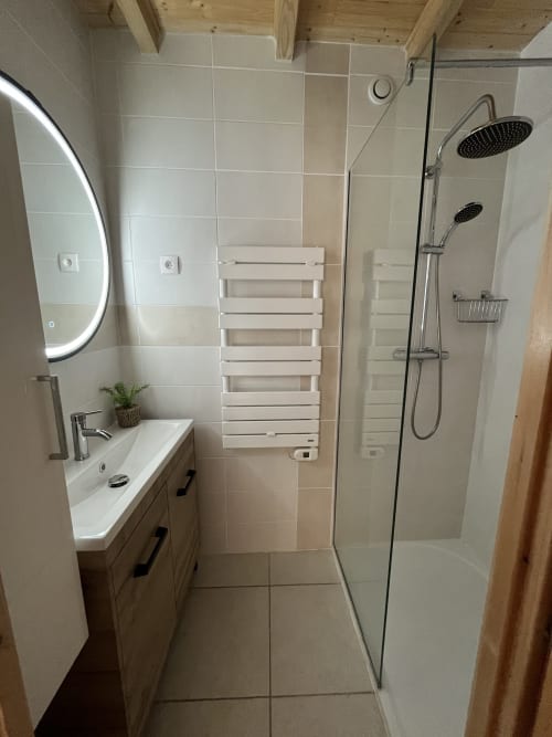 Salle de bain moderne du gîte Le Cocon De Curson avec carrelage blanc, douche à l'italienne avec pluie de tête, bien éclairée
