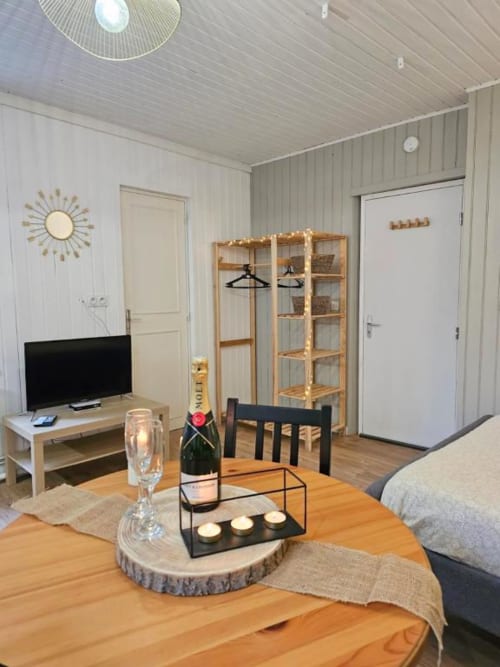 Studio moderne aux Gîtes Saint Valery En Caux avec table à manger, TV, kitchenette et rangements en bois