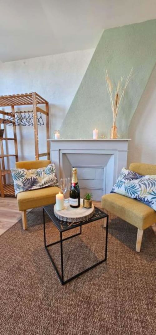 Salon élégant avec mur d'accent vert sauge, cheminée, deux fauteuils moutarde et champagne à La Jungle