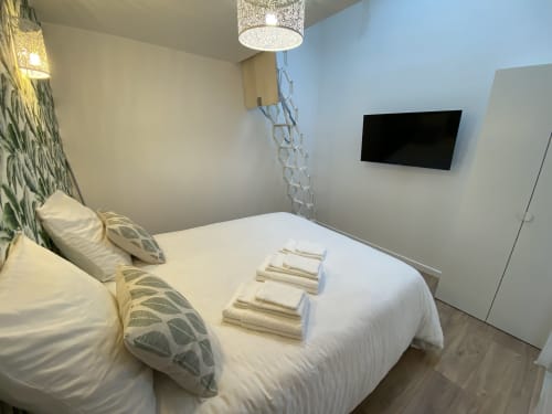 Modern bedroom at La Maison Blanche in Bouguenais with white bed, fresh towels, wall-mounted TV, and contemporary décor