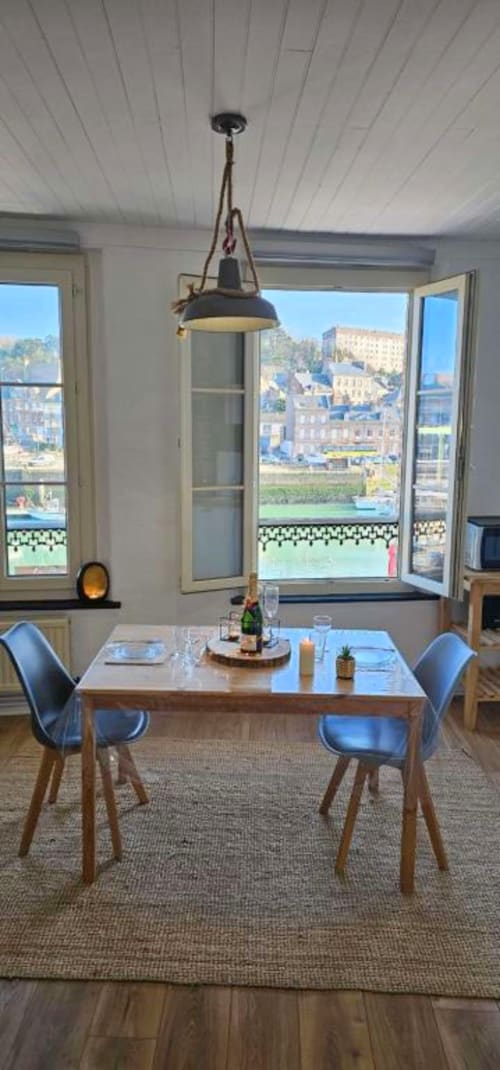 Salle à manger contemporaine avec vue sur mer dominant le port de Saint Valery En Caux, table en bois, chaises bleues, suspension