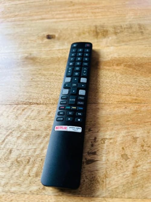 Control remoto negro con botones de Netflix y Prime Video sobre mesa de madera en apartamento de La Palma