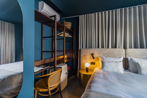 Studio moderno de hotel no Porto com paredes azul-esverdeado, beliche de madeira, escrivaninha, móveis amarelos e roupa de cama neutra