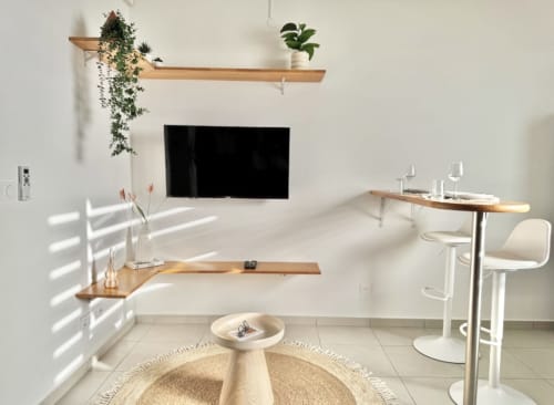 Studio moderne à Cayenne avec étagères flottantes en bois, TV murale, bar et mobilier minimaliste
