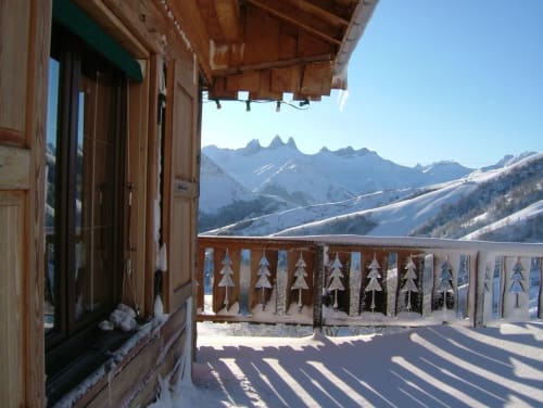 Snowy mountain balcony view at Chalet La Louvière with Alps peaks and wooden railing in winter