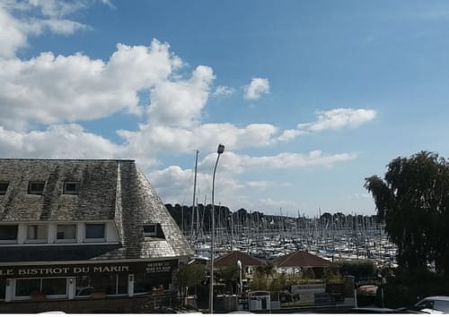 Vue de la marina depuis Mer et Maisons à La Trinité sur Mer avec voiliers, bâtiments en pierre et ciel bleu
