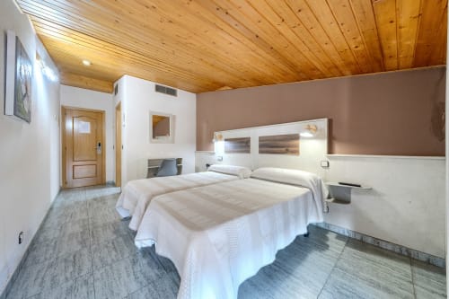 Habitación doble con techo de madera en Hostal El Molino de Collado Villalba, con dos camas y equipamiento moderno