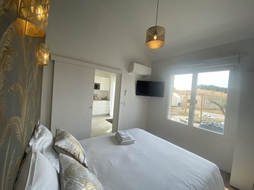 Modern bedroom at La Maison Blanche BnB in Bouguenais with queen bed, garden view windows, TV, and pendant lighting