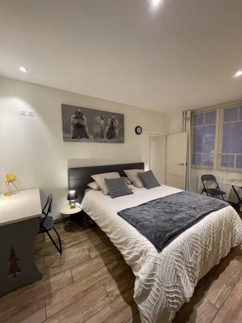 Chambre moderne à La Montagnette B&B à Moutiers avec lit queen-size, bureau et vue sur la ville par de grandes fenêtres