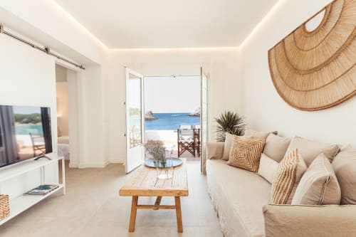Apartamento moderno y luminoso en Las Golondrinas con sofá beige, vista al mar desde puertas abiertas, muebles de madera y estilo mediterráneo