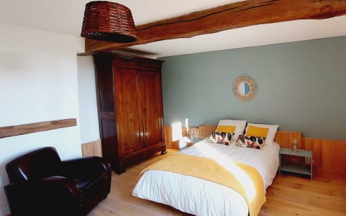 Spacious bedroom in Orchids cottage at Les Gites de Campardon with queen bed, wooden beams, and sage green walls.