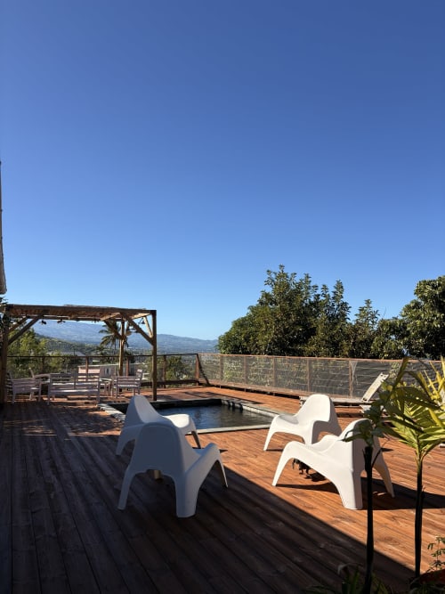 Terrasse sur le toit de la Villa Maraloupia à Les Avirons avec piscine, chaises longues blanches et vue montagne