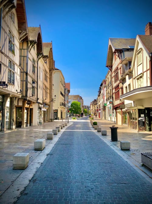 Rue piétonne historique à Troyes avec façades à colombages traditionnelles et boutiques de chaque côté sous un ciel bleu dégagé