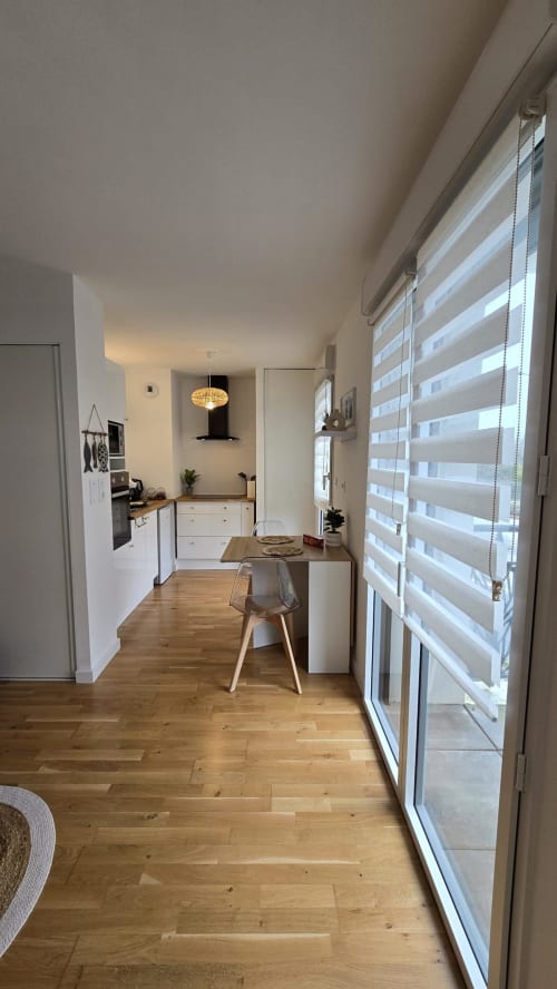 Modern kitchen-dining area in Ô KASTEL apartment, La Fôret-Fouesnant, with wooden flooring, white cabinetry, and striped