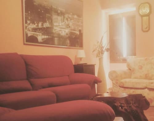 Acogedora sala en el apartamento La Viña de Casas Rurales con sofá rojo, vista de ciudad enmarcada y sillón crema