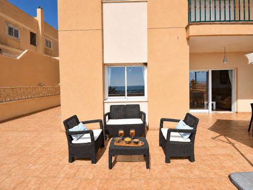 Spacious terrace at Apartamentos El Calón Playa with sea views, black wicker furniture, and coastal setting in Cuevas del