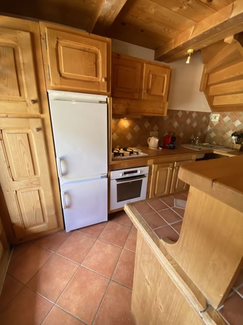Cuisine équipée avec meubles en bois, réfrigérateur blanc et cuisinière à gaz dans l'appartement Vorès à La Ferme des Georgières