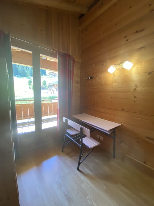Espace de travail en bois à La Ferme des Georgières avec bureau, chaise et vue montagne par les portes vitrées