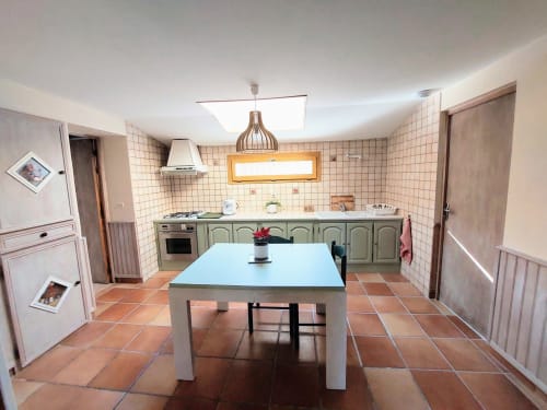 Orchids cottage kitchen at Les Gites de Campardon with dining table, green cabinetry, and terracotta tile floors