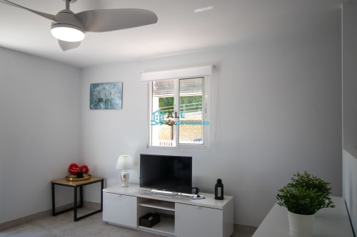 Casa de las lirio blanco: recámara moderna con televisor, ventilador de techo y vistas al balcón en entorno montañoso