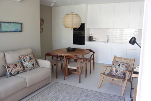 Modern open-plan apartment at Break Lovers Tavira with dining table, sofa, kitchen, and woven pendant light