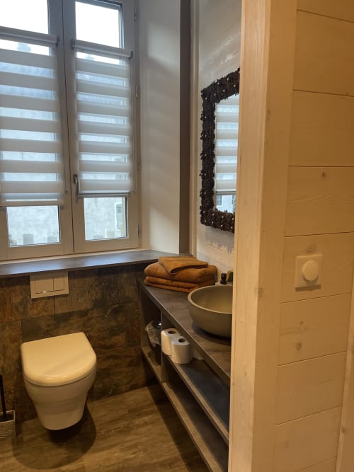 Salle de bains moderne à La Montagnette B&B à Moutiers avec toilettes murales, vasque, miroir et fenêtre à rayures