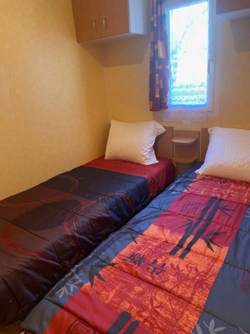 Lits jumeaux aux courtepointes colorées dans le mobil-home Auvergne du Relais de La Mirpe, Bergerac