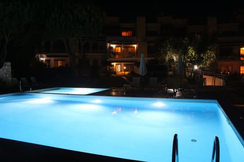 Illuminated swimming pool at night with terracotta buildings at Break Lovers apartment in Tavira, Portugal