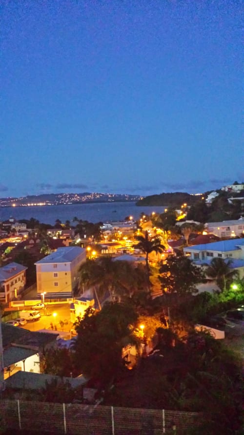 Vue du balcon de l'appartement Kay Betty au crépuscule surplombant la ville illuminée des Trois-Îlets et la mer des Caraïbes, Martinique