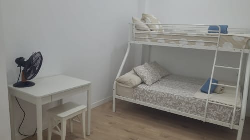 Camera da letto compatta a Santa Cruz de Tenerife con letto a castello bianco, scrivania, ventilatore e pavimento in legno