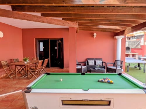 Sala de billar Villa Rodrigo con mesa de billar verde, paredes coral, vigas de madera, comedor y zona de descanso en Sara & Gino